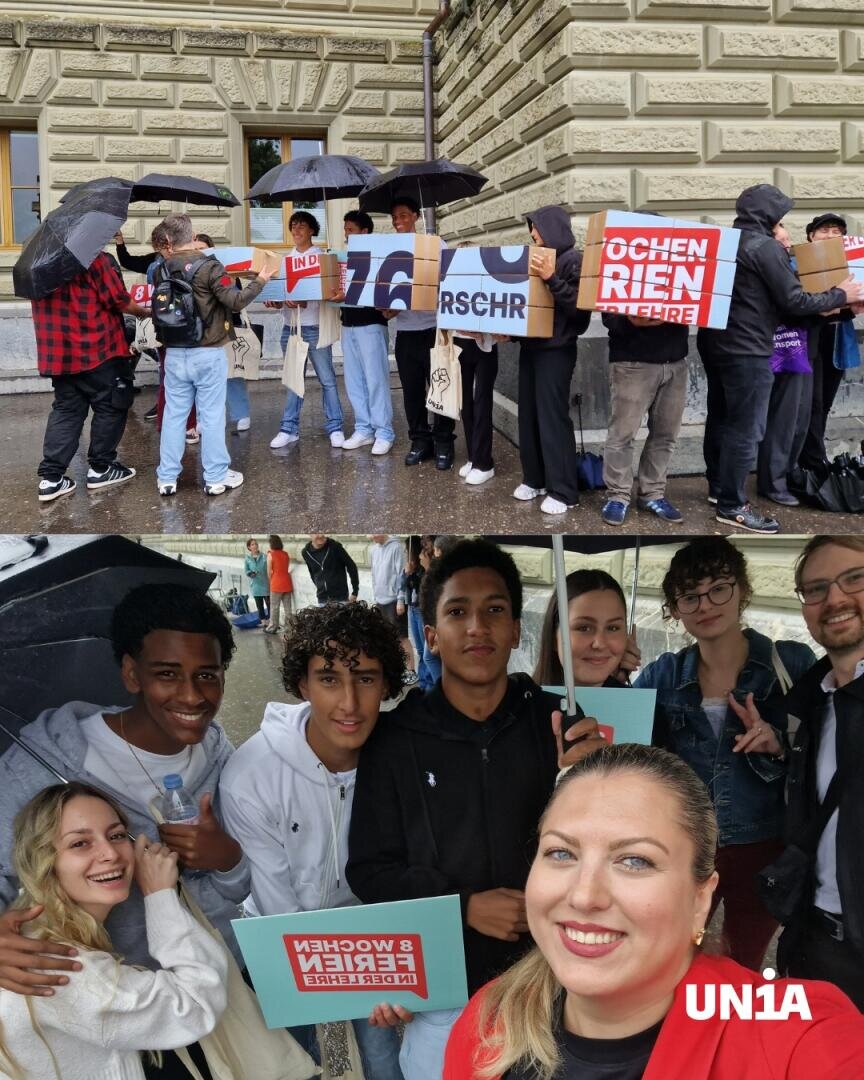 Eine Gruppe von Menschen steht draußen im Regen und hält Protestschilder und Regenschirme in den Händen; darunter posiert eine lächelnde Gruppe mit Wahlplakaten für ein Selfie. In der Ecke ist das UNIA-Logo zu sehen.