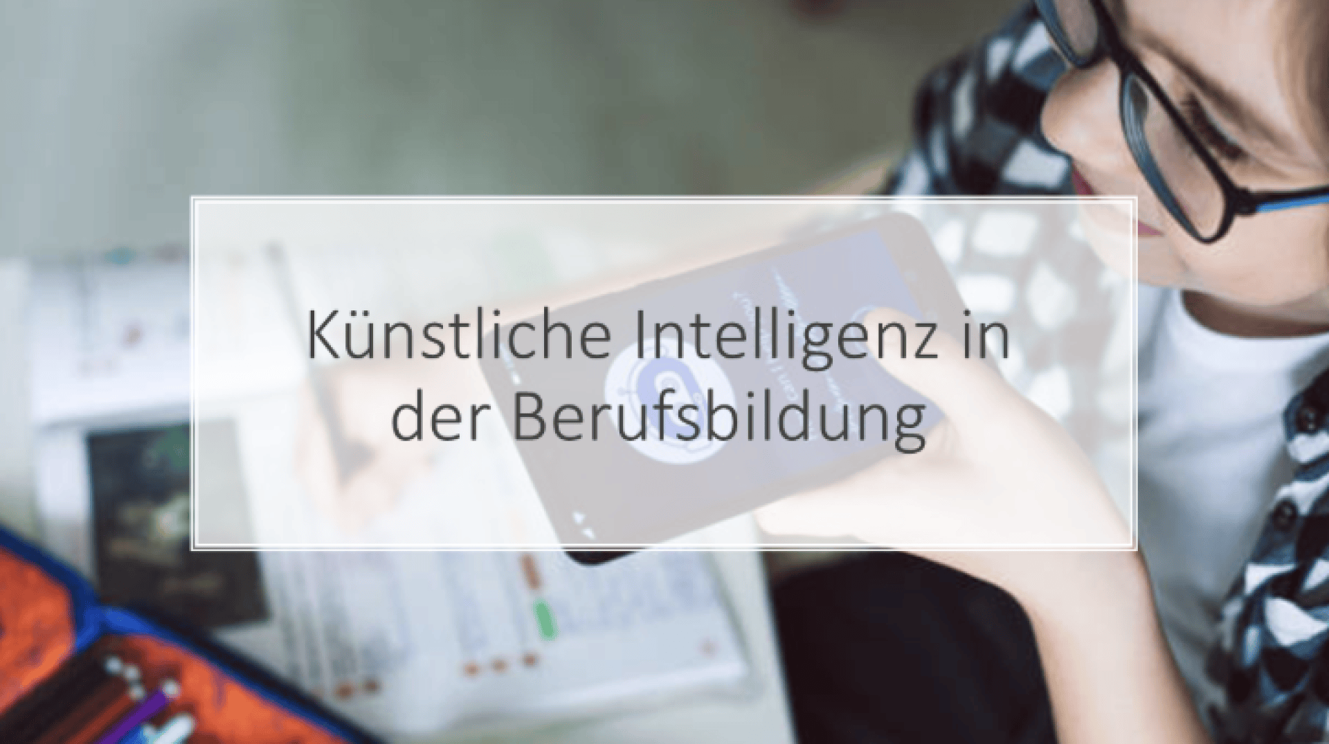 Eine Person mit Brille nutzt ein Smartphone, während sie am Schreibtisch lernt. Der eingeblendete Text auf Deutsch lautet „Künstliche Intelligenz in der Berufsbildung“, was so viel bedeutet wie „Künstliche Intelligenz in der beruflichen Bildung“.