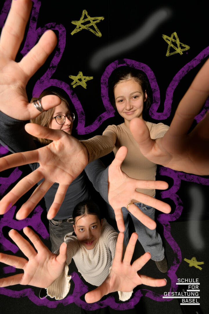 Drei junge Menschen strecken lächelnd ihre offenen Hände in Richtung Kamera aus. Um sie herum sind violette Schnörkel und gelbe Sterne gezeichnet. In der rechten unteren Ecke steht der Schriftzug „Schule für Gestaltung Basel“.