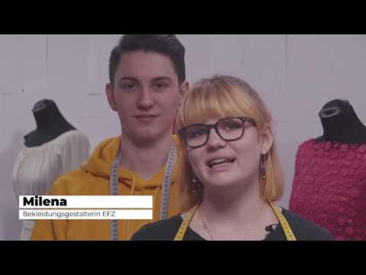Zwei junge Menschen stehen vor Schaufensterpuppen. Die Frau vorne, die eine Brille und ein gelbes Maßband um den Hals trägt, spricht. Der Mann hinter ihr trägt einen gelben Kapuzenpulli. Der Text lautet: Milena Bekleidungsgestalterin EFZ.